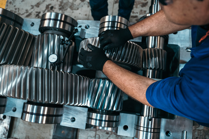 Industrial worker handling precision-machined metal components, representing the application of engineered materials in manufacturing.