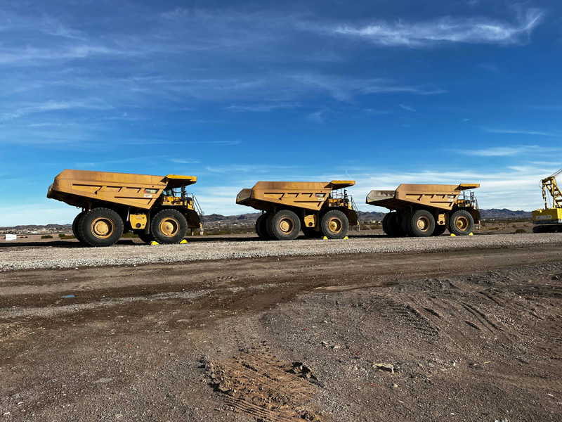 Large mining haul trucks operating in an open-pit mine, illustrating the demanding conditions of mineral extraction activities.