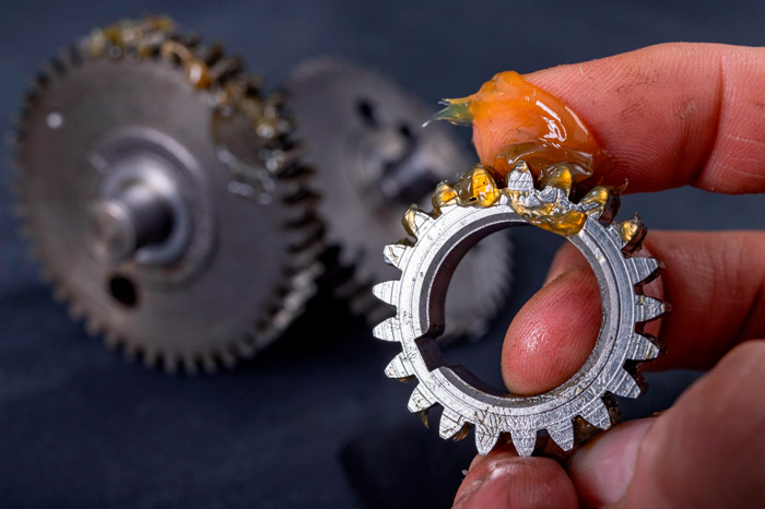 Grease shown alongside gears, demonstrating how oil selection impacts efficiency, wear protection, and equipment lifespan.