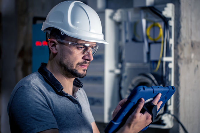 Industrial maintenance professional using a tablet to plan equipment inspections and maintenance activities.